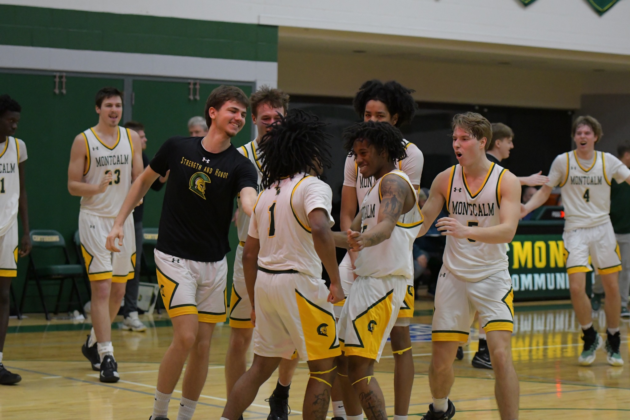 MCC Men's Basketball team celebrate together on the course after a game.