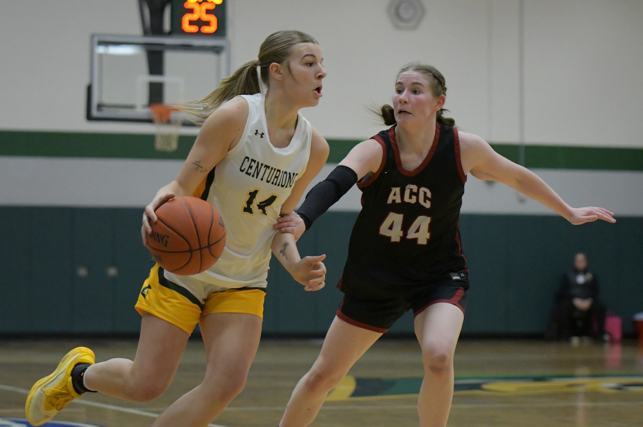 MCC women's basketball player dribbling the ball around an oppossing player on the court during a game. She is wearing uniform number 14.