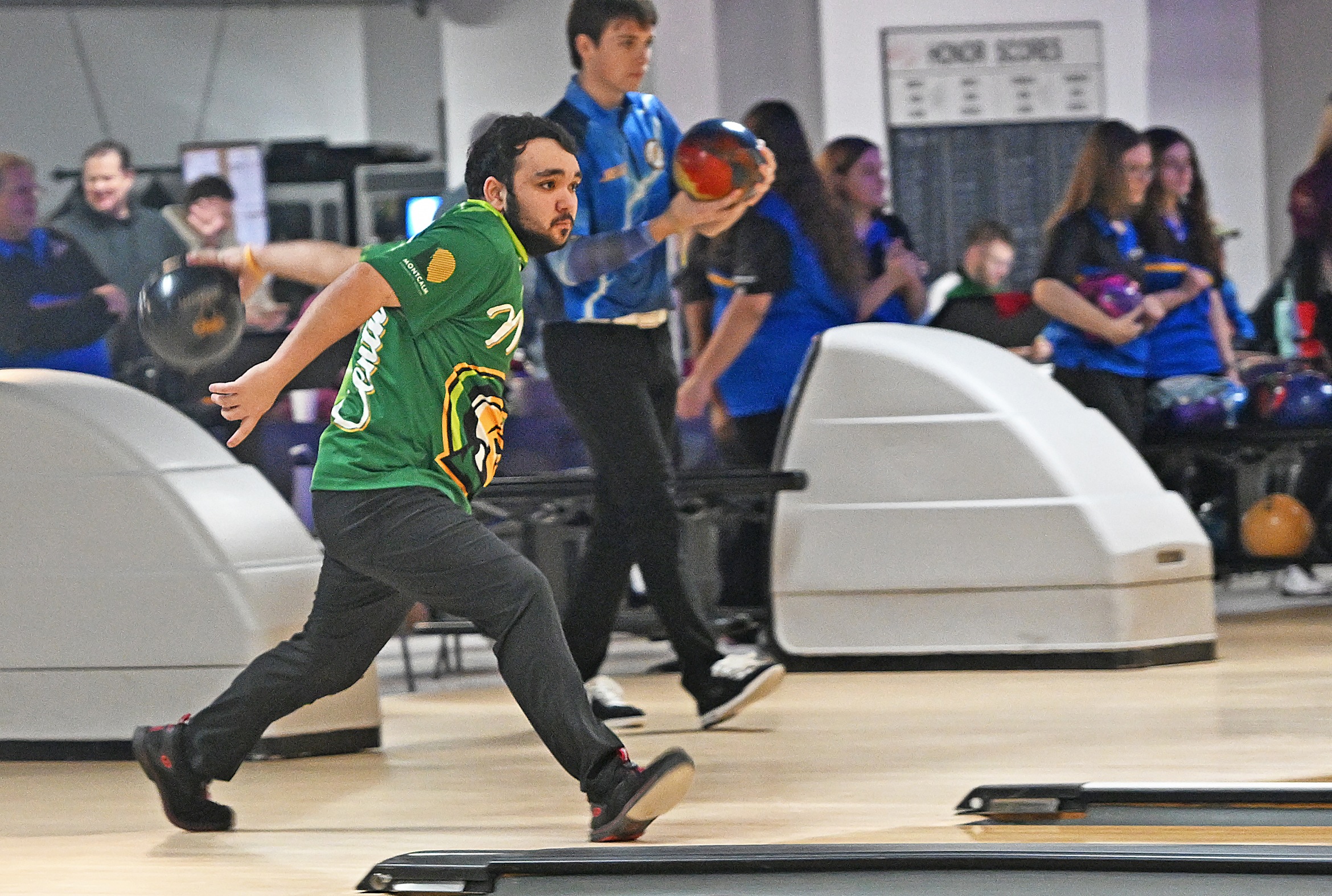 Men's bowling team member preparing to release the ball down the lane. 